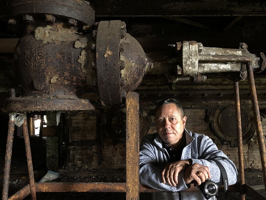 portrait of man in industrial setting holding camera