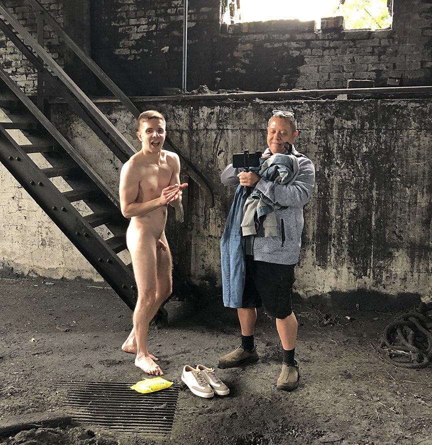 man assisting nude model by carrying clothing