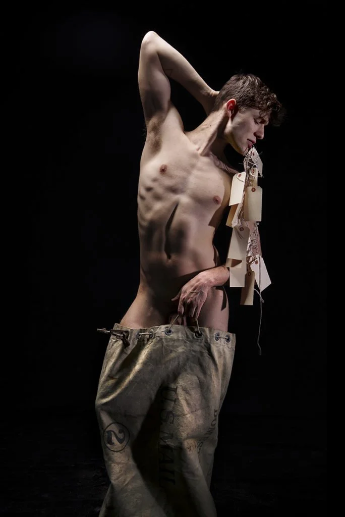 nude man in old mail pouch holding shipping tags