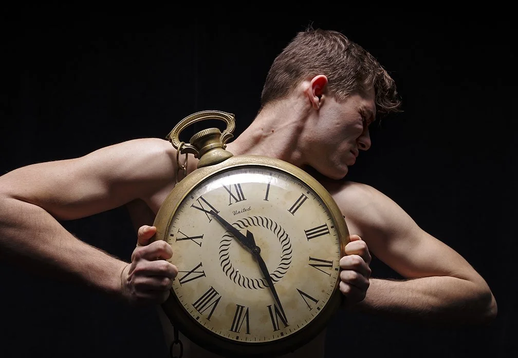 dark studio shot of man holding huge pocket watch