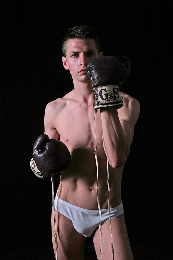 man standing in dark studio in underwear with boxing gloves