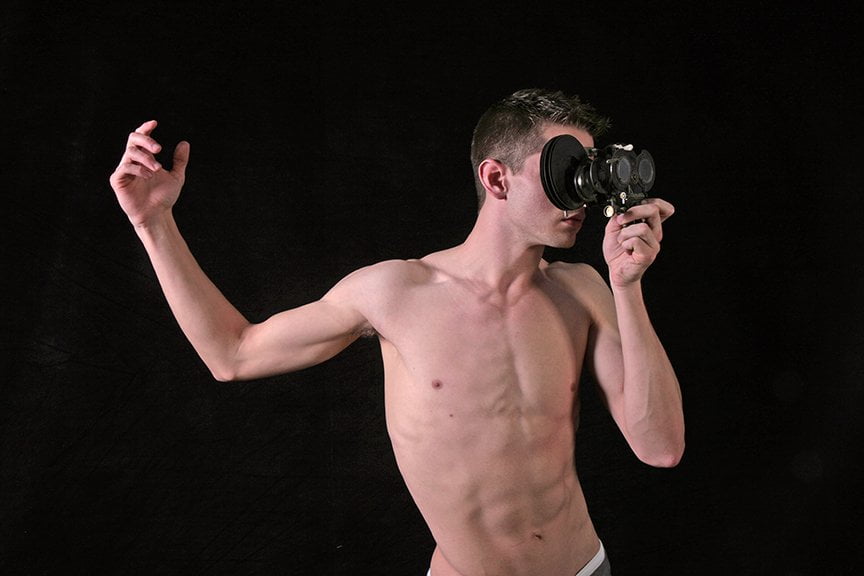 shirtless man holding looking through optical instrument with upheld arm