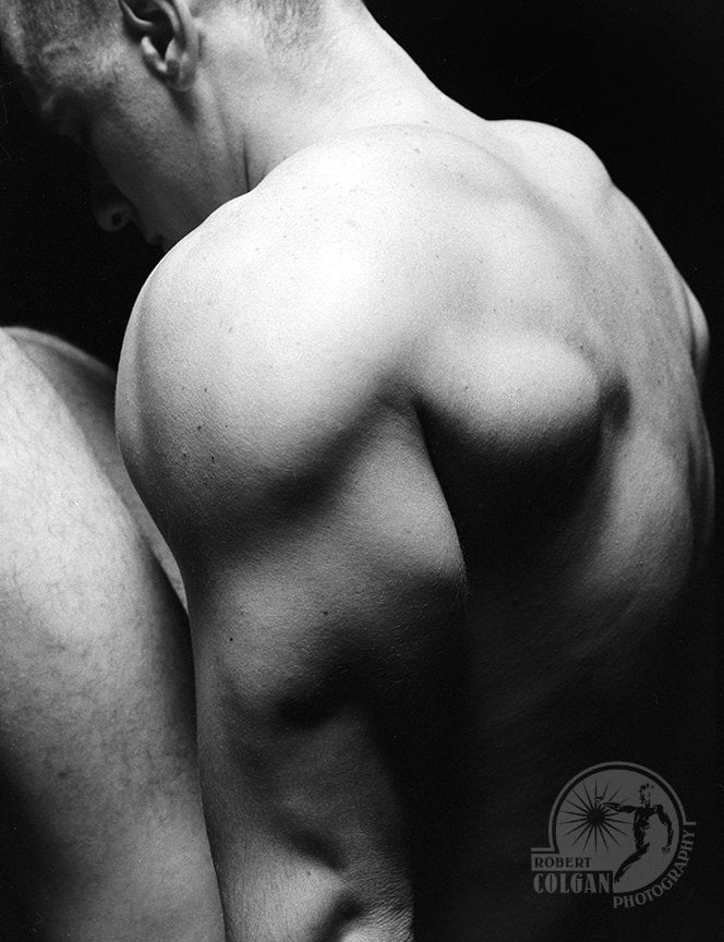 partially visible nude man in darkened studio