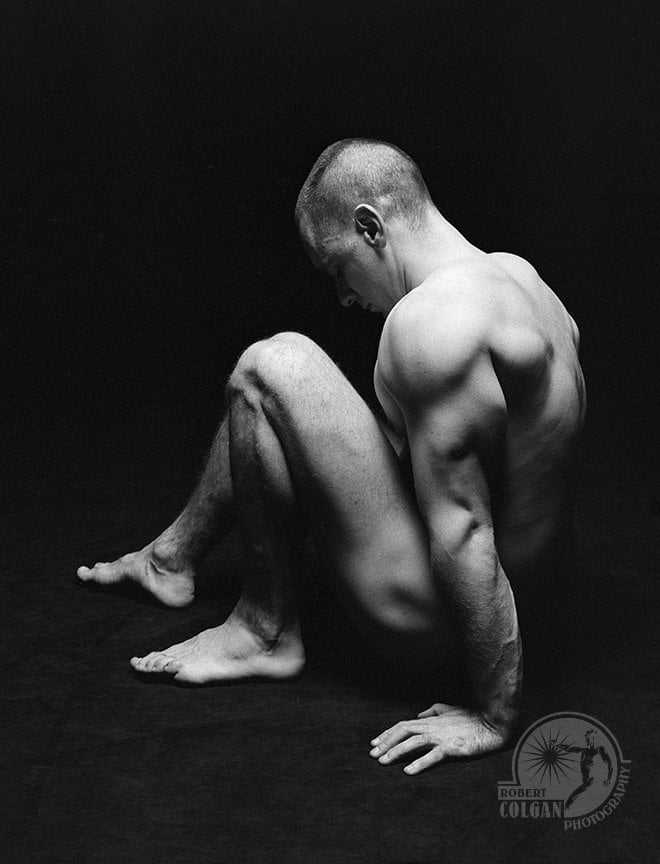 partially visible nude man in darkened studio