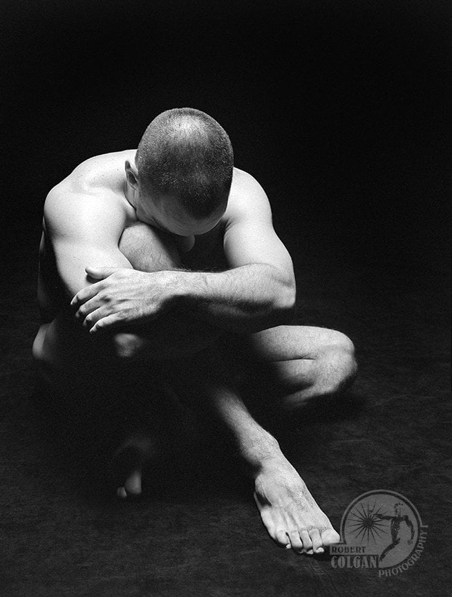 partially visible nude man in darkened studio