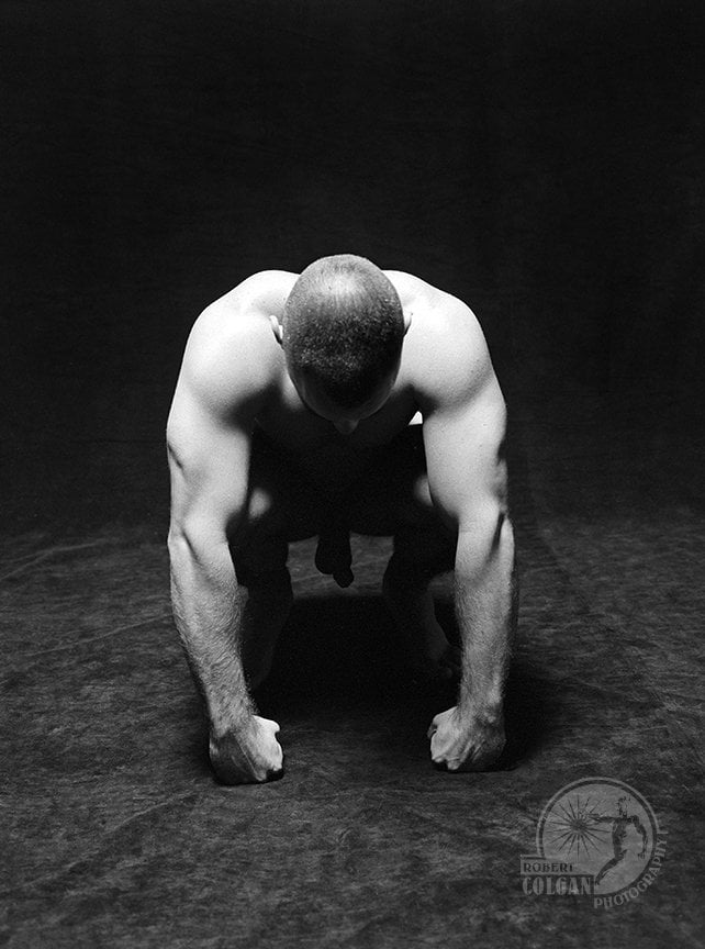 partially visible nude man in darkened studio