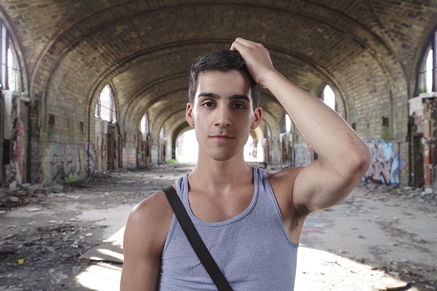 Man looking directly at viewer with abandoned train station in background