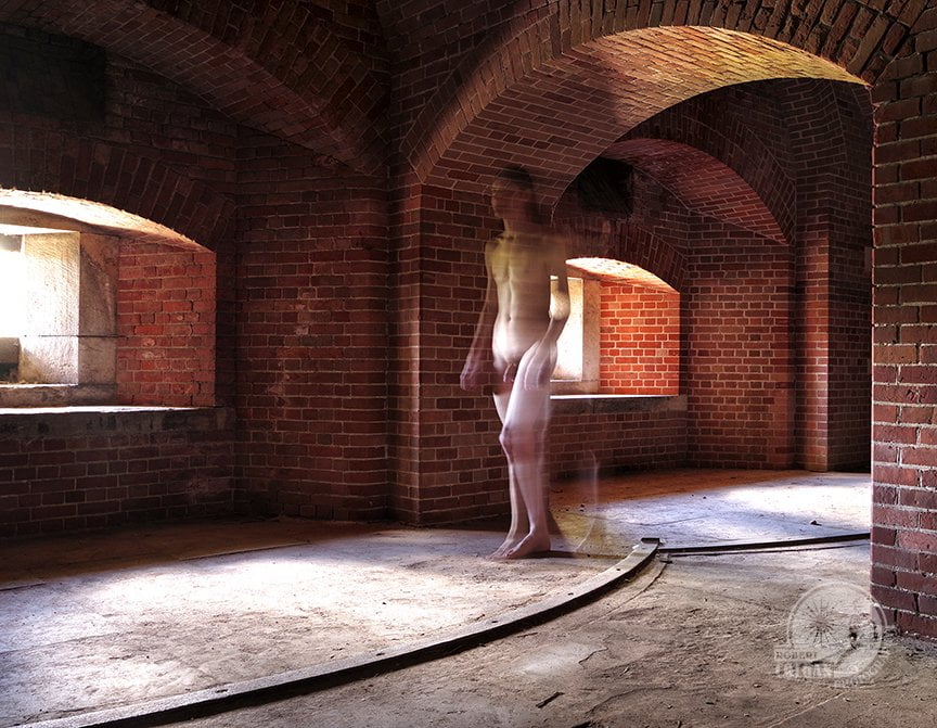 Blurred image of nude man walking through dim light of old gun emplacements