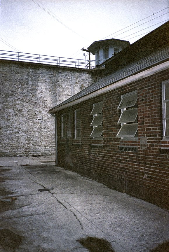 small brick building with wall and guard tower in background