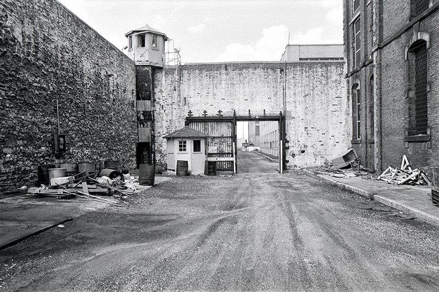 gate into Penitentiary with tower above and cellblock to the right side