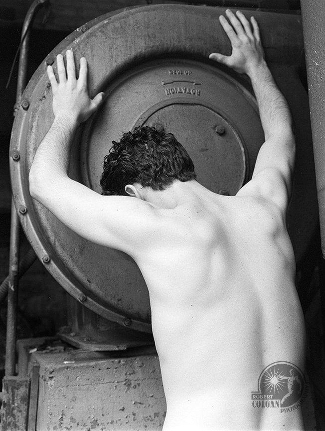 shirtless man with back to camera grasping side of circular machine