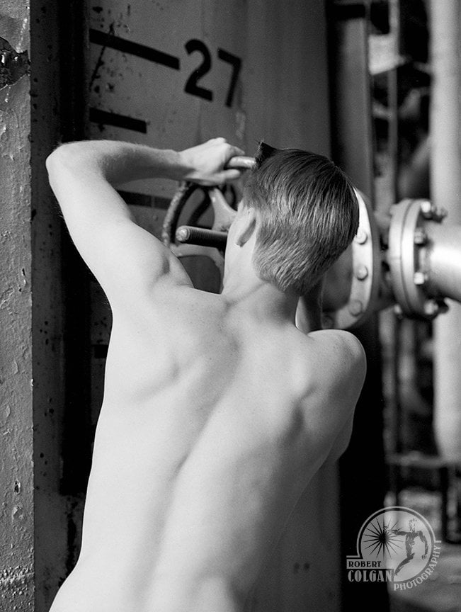 shirtless man turning wheel on pipes