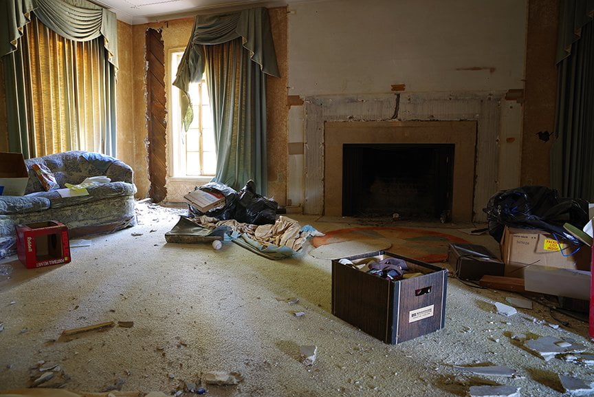 darkened view of abandoned room in old house with junk and furniture