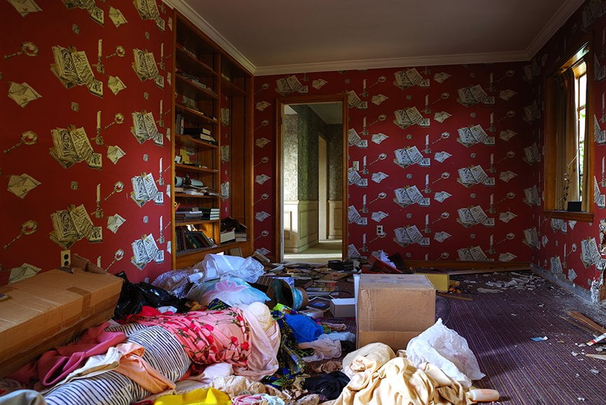abandoned room with bookcases and clothing strewn across the floor