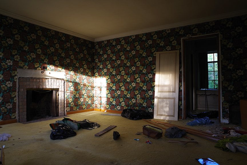 darkened view of wallpapered room with junk on floor