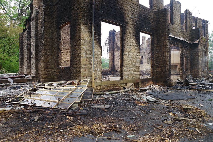 smoldering remains of house after it was set aflame by fire department