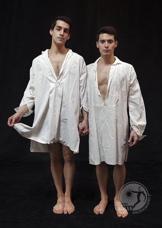 two men stand in nightshirts looking at the camera