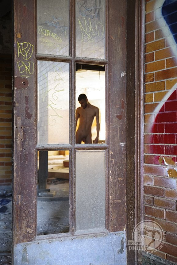 faint oiutline of nude man shot through old door with missing glass