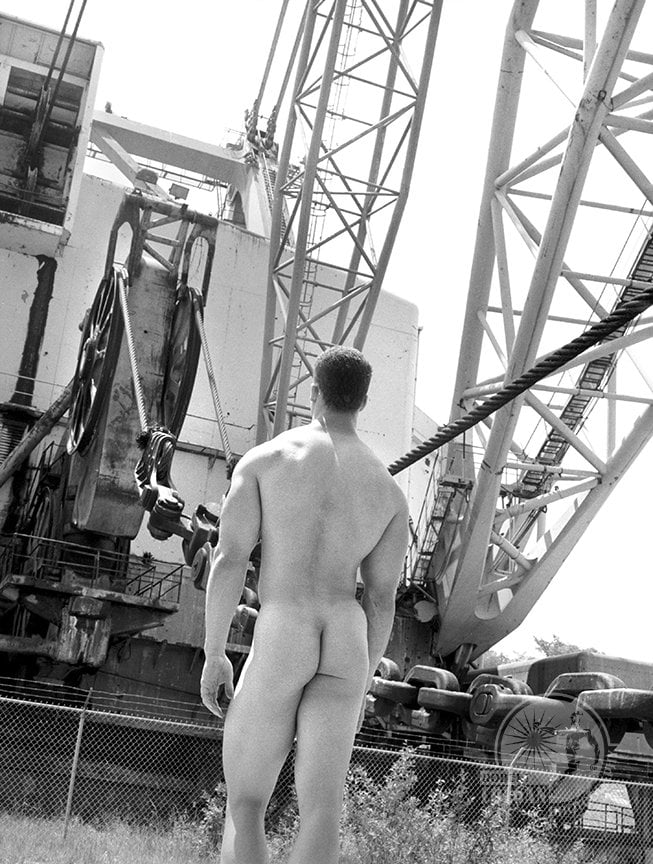 nude man with back to camera facing huge strip mine shovel