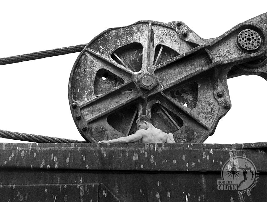 partially visible man among giant pulley and bucket