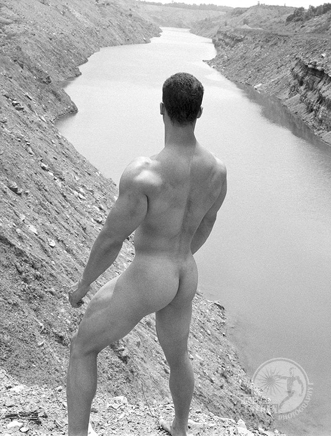 nude man stands above huge deep trench cut by the strip mine shovel