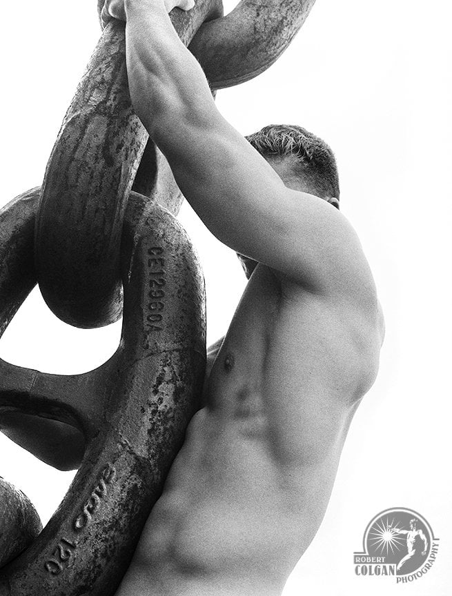 close-up of nude man clinging to giant chain link