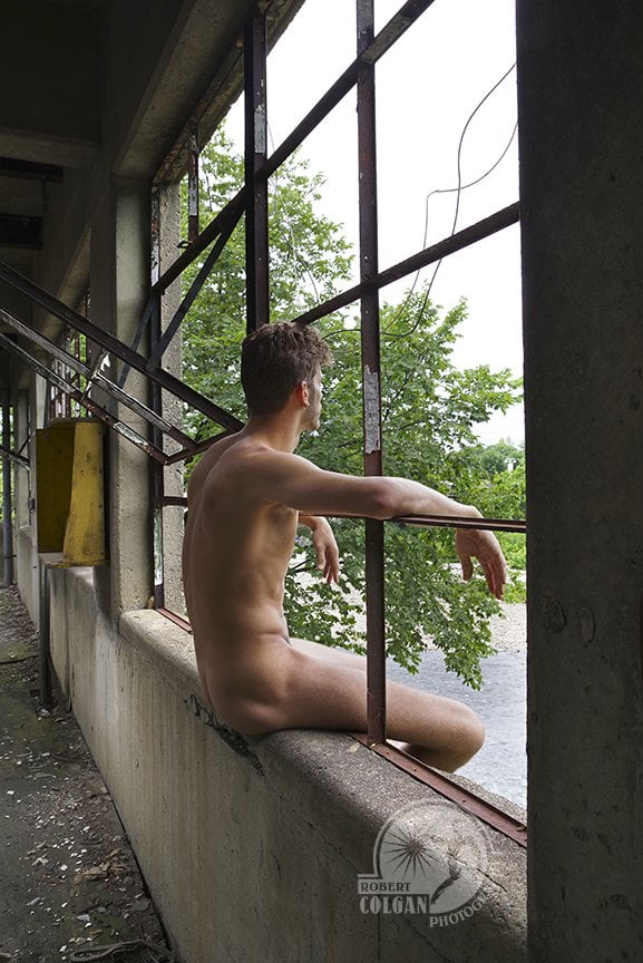 naked man sitting in remains of broken windows