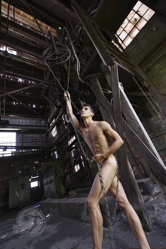 nude male figure intertwined in chain from pulley above