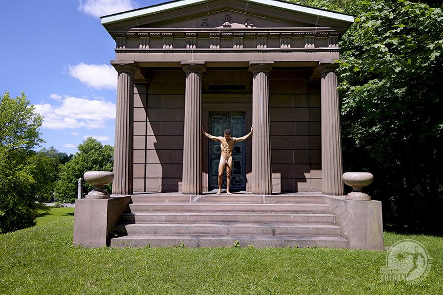 nude man standing between columns of mausoleum arms outstretched