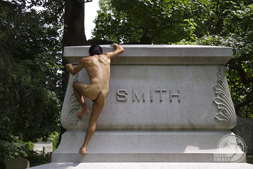 nude man climbing atop a monument