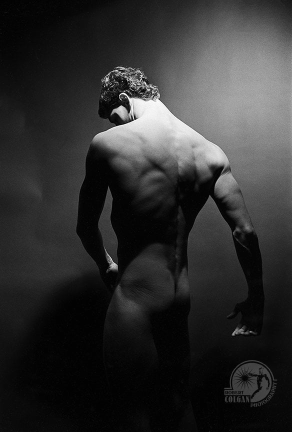 nude male with back to camera in dim studio lighting