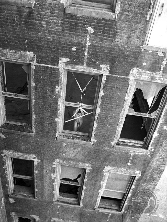 view looking down old building with nude man standing in open window