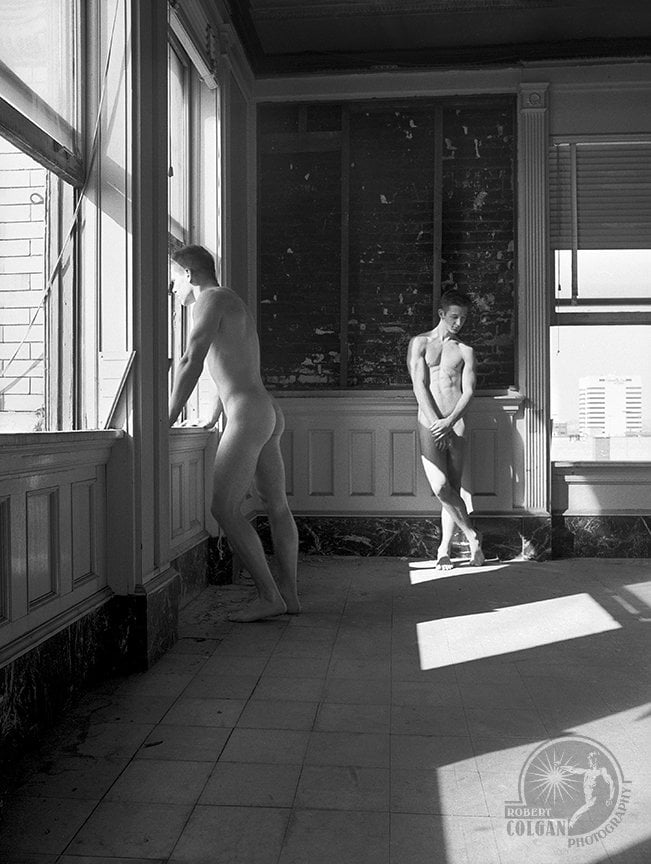two nude men in empty room of abandoned building looking in opposite directions