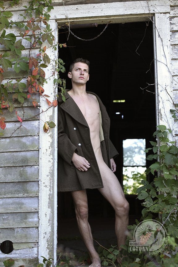 partially nude man in abandoned house looking out doorway to outside