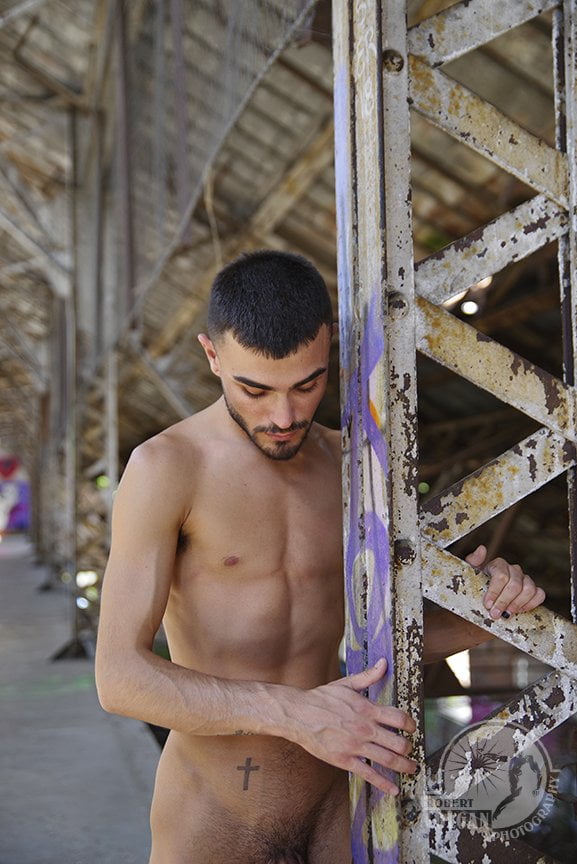 nude man standing beside supporting girder