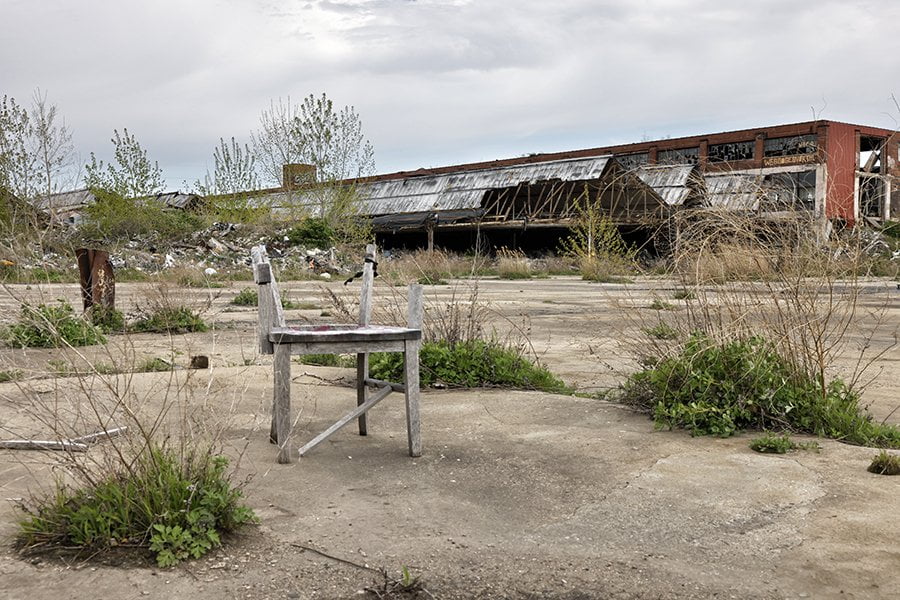 broken chair sits outside remains of old factory