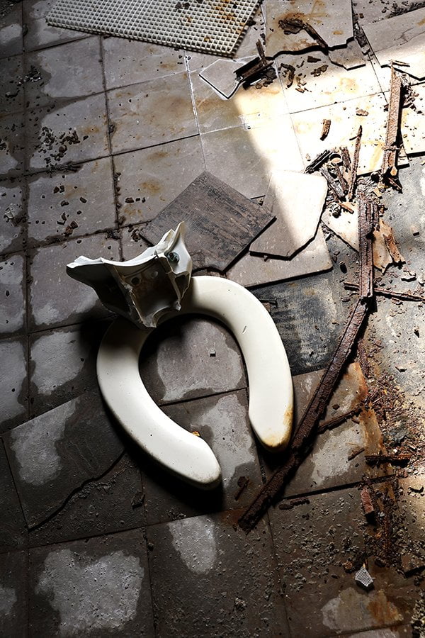 broken toilet seat laying on floor of old factory