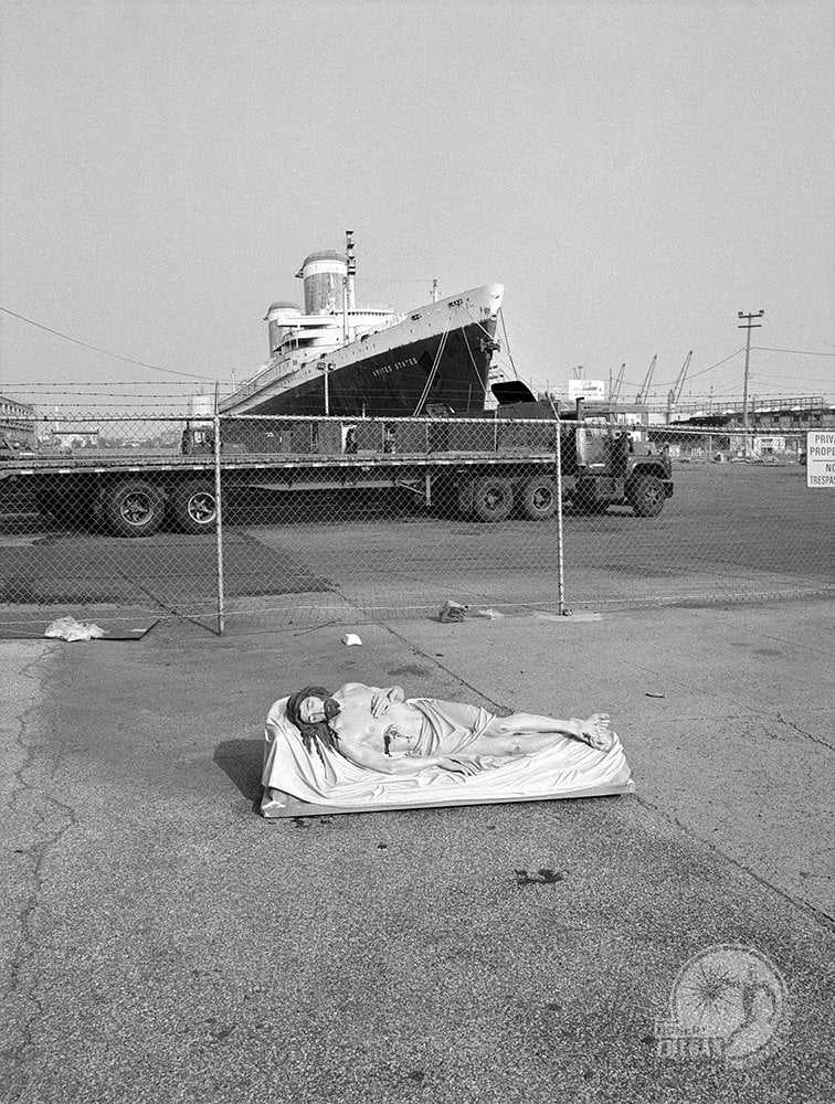 statue of Jesus in front of rusting steamship, SS United States