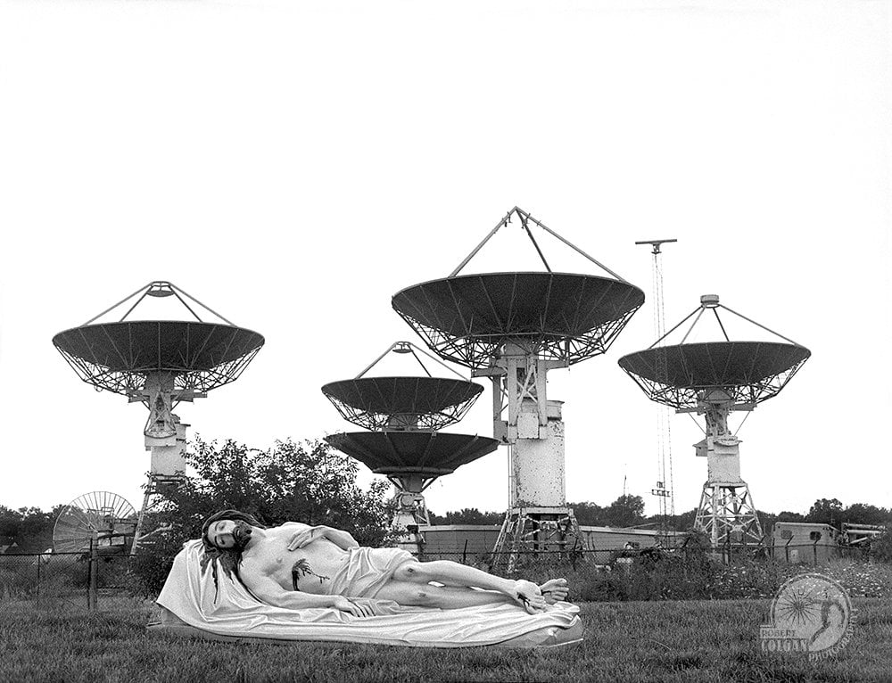 statue of Jesus in front of satellite array