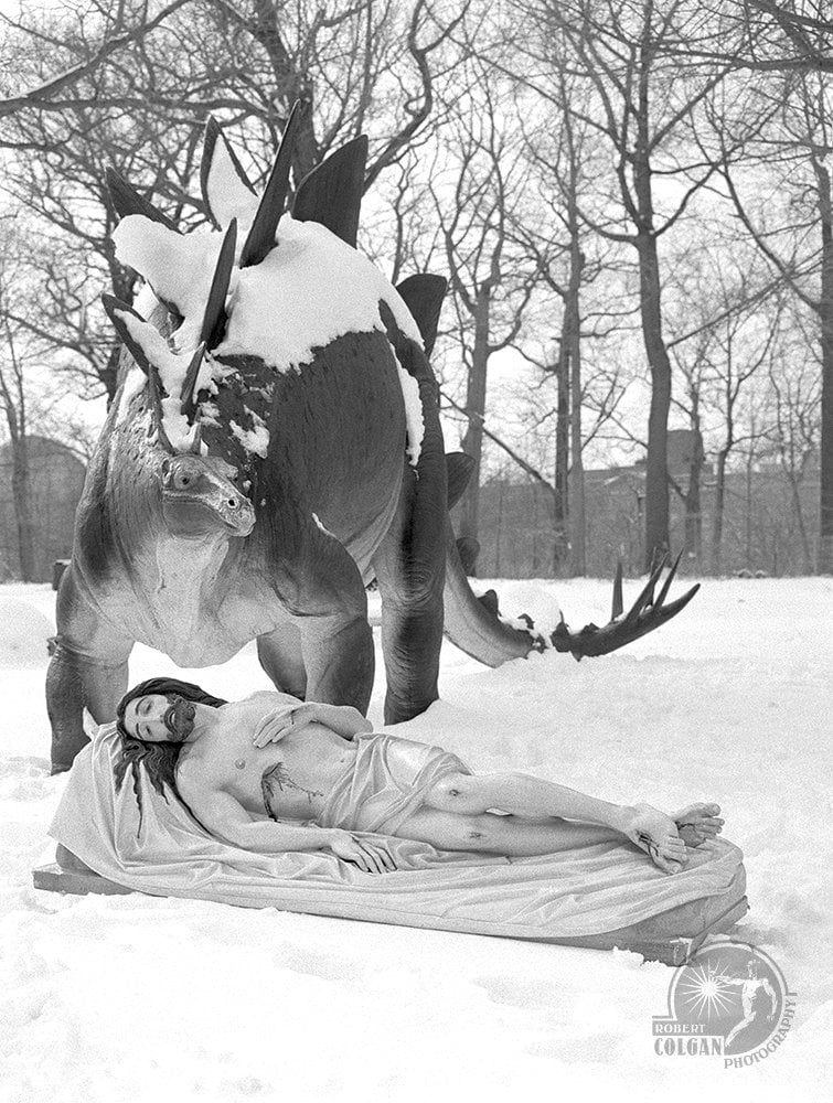 statue of Jesus in snow with stegosaurus