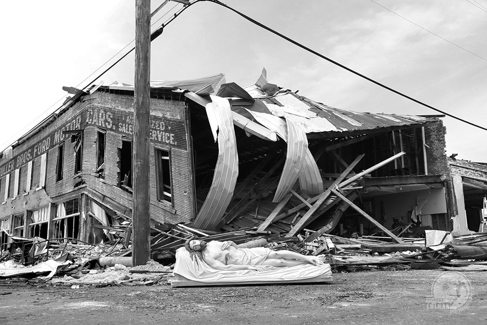 statue of Jesus in front of tornado damaged building