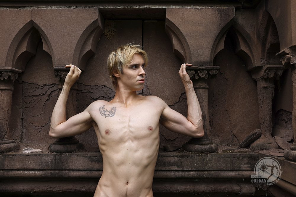 shirtless man leans against craved sandstone pillars