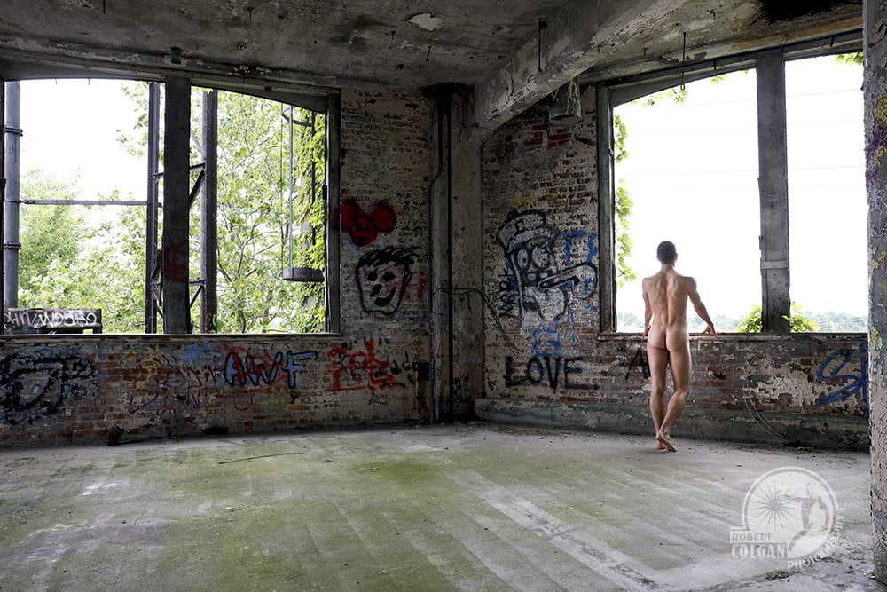 large open room in old factory with nude man looking out window