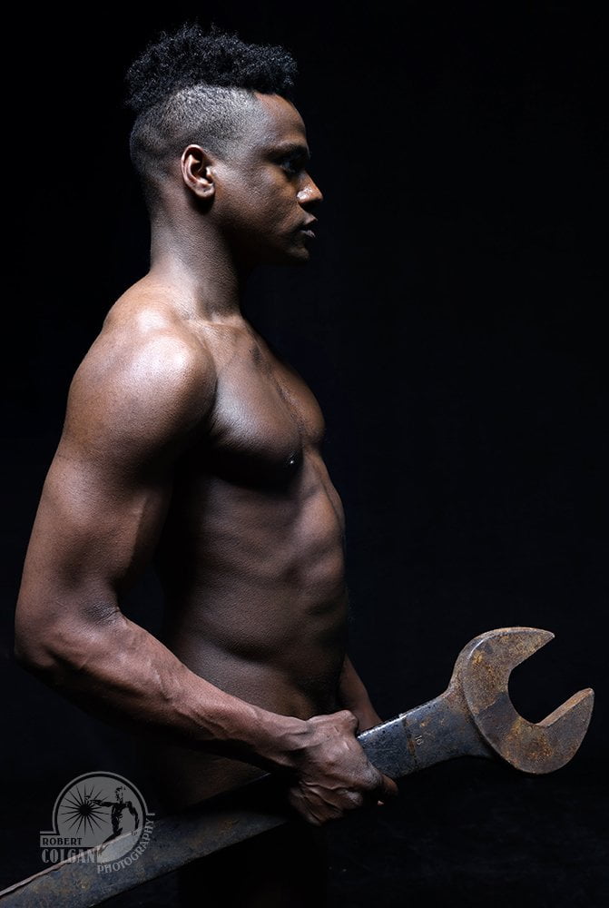 profile of nude man grasping large wrench