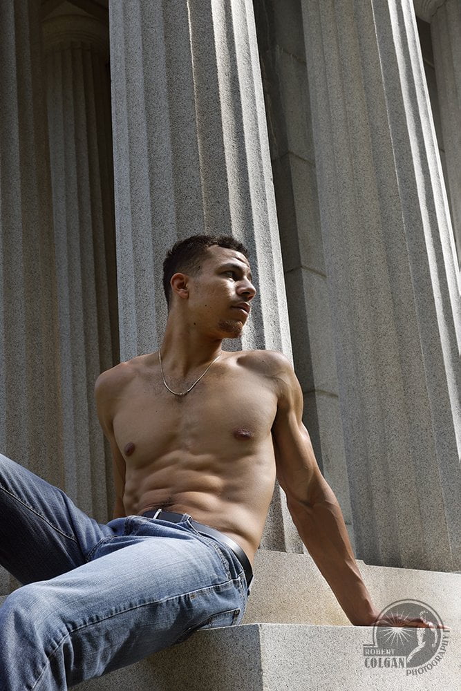 shirtless man sitting beside a classical temple