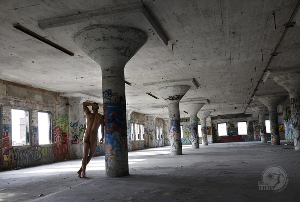 angular shot of nude man in empty factory