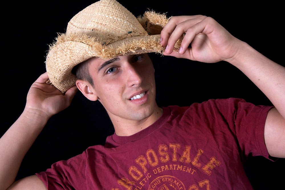 portrait of man with his hands grasping straw hat