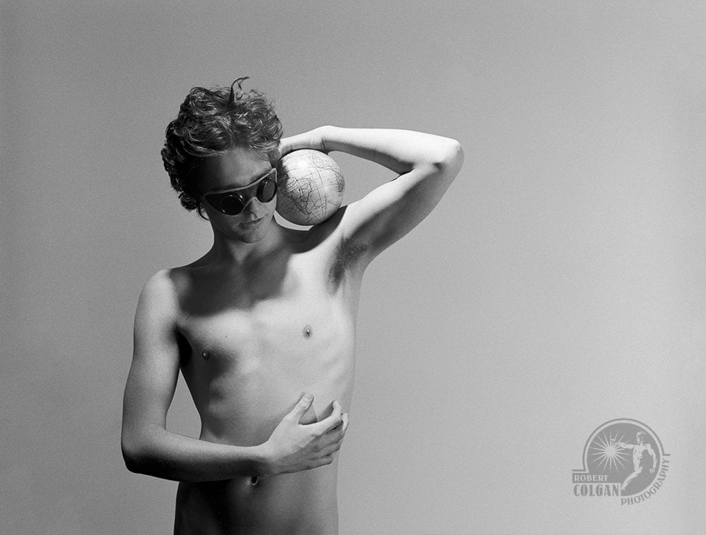 shirtless man wearing goggles while holding globe on shoulder