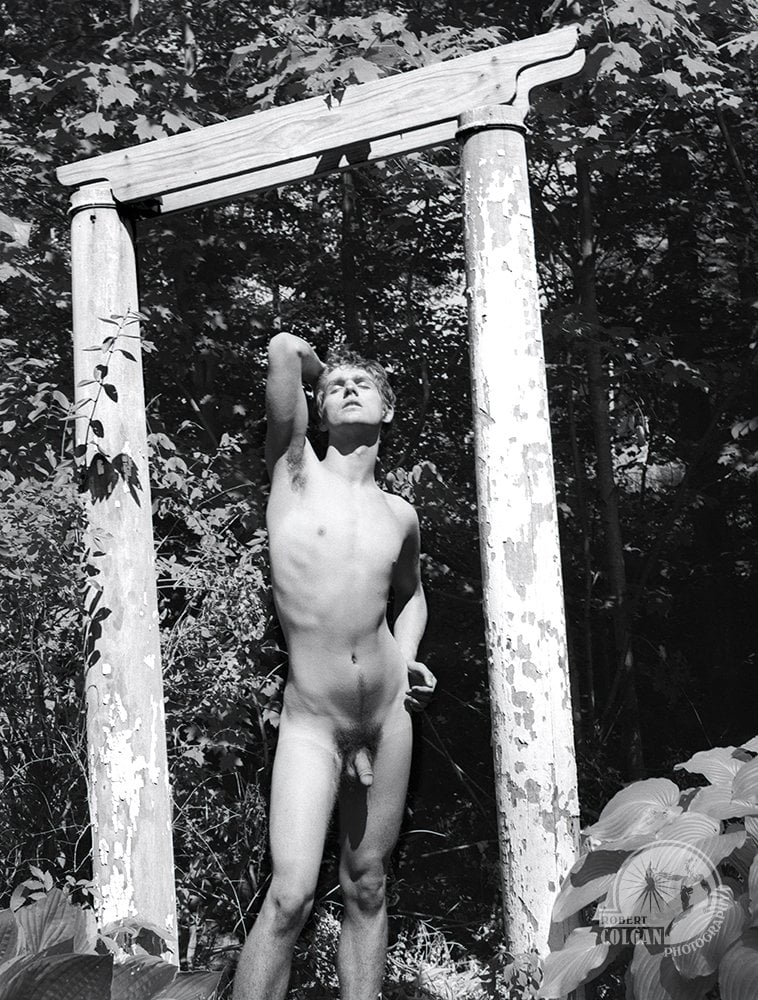 nude man outside stretches between two columns