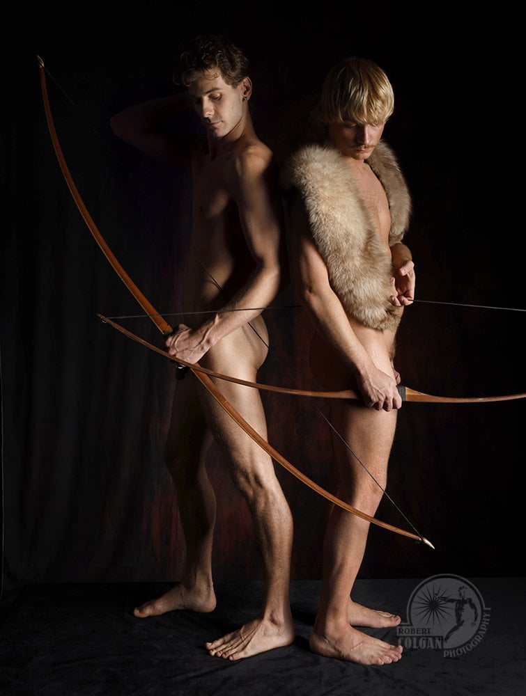 two nude men standing back to back with bows
